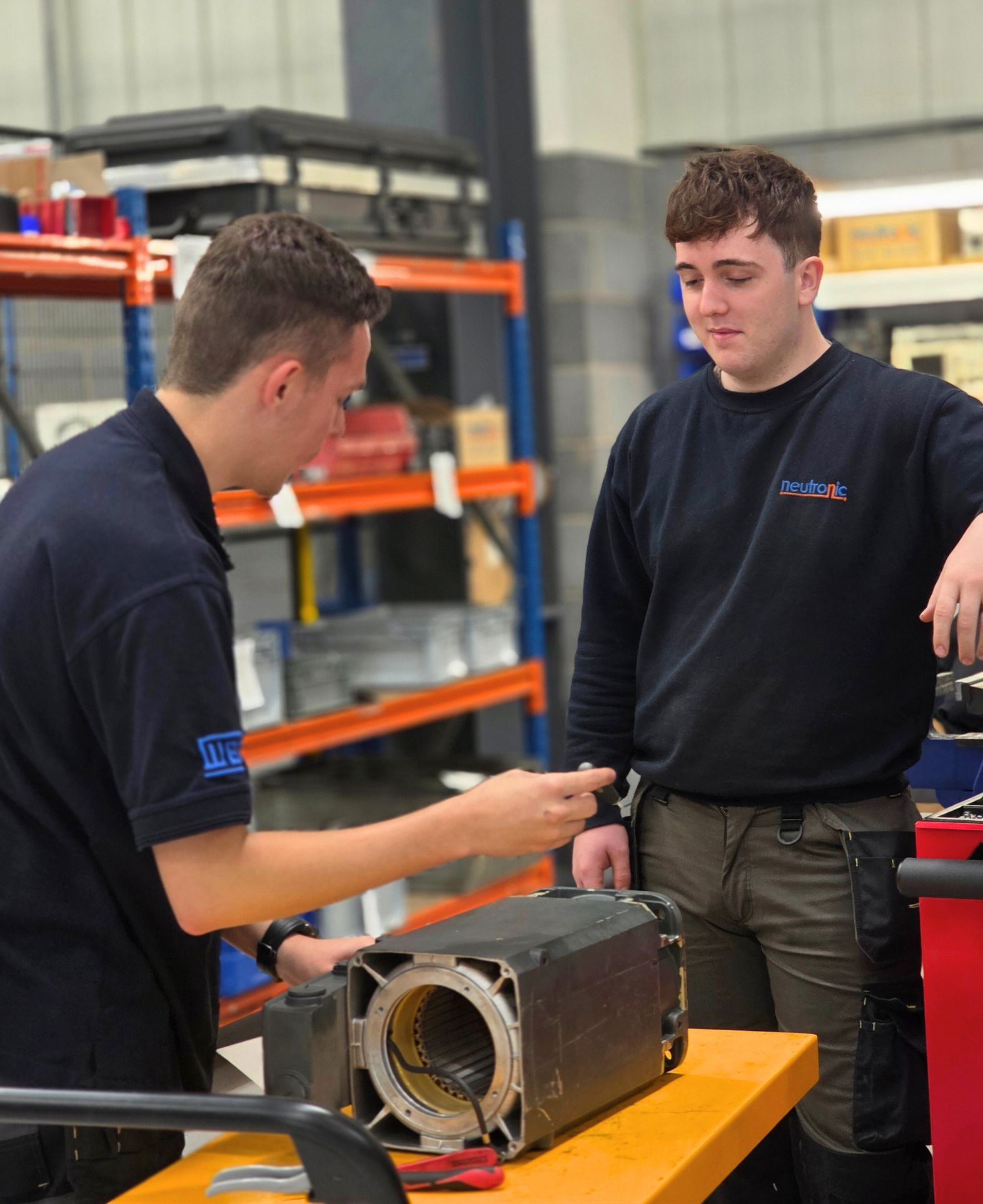 Technician performing servo motor repair at Neutronic Technologies workshop, inspecting and working on a disassembled servo motor placed on a workbench. Servo Motor Repairing process with servo motor parts for professional servo motor repair and Servo Motor Repairs services