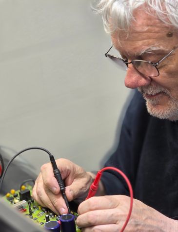 Industrial controller repairs carried out by a Neutronic Technologies engineer diagnosing and testing an industrial control PCB in a specialist repair workshop.