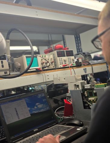 An engineer is performing servo drive repairs at a technical workbench using diagnostic software and electronic test equipment.