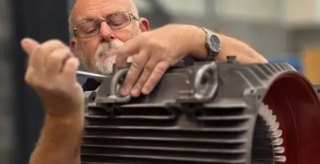 A neutronic engineer inspecting and repairing industrial electric motors and gearboxes used in automation systems for distribution centres.