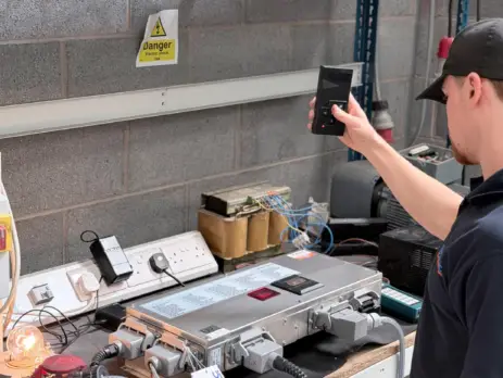 LJU Automation testing and diagnostics service at Neutronic Technologies with engineer inspecting industrial automation control unit and electronic repair system in workshop.