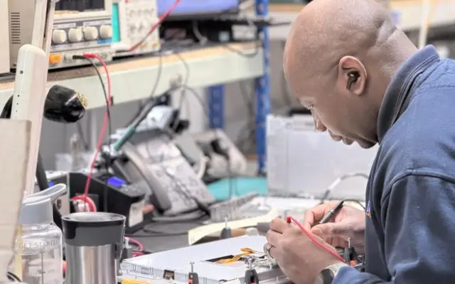 An industrial HMI repair specialist testing touchscreen and operator interface electronics in the UK repair workshop.